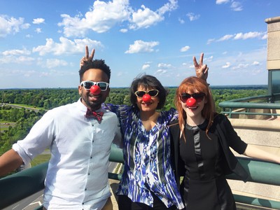 Three office workers with clown noses on smiling.